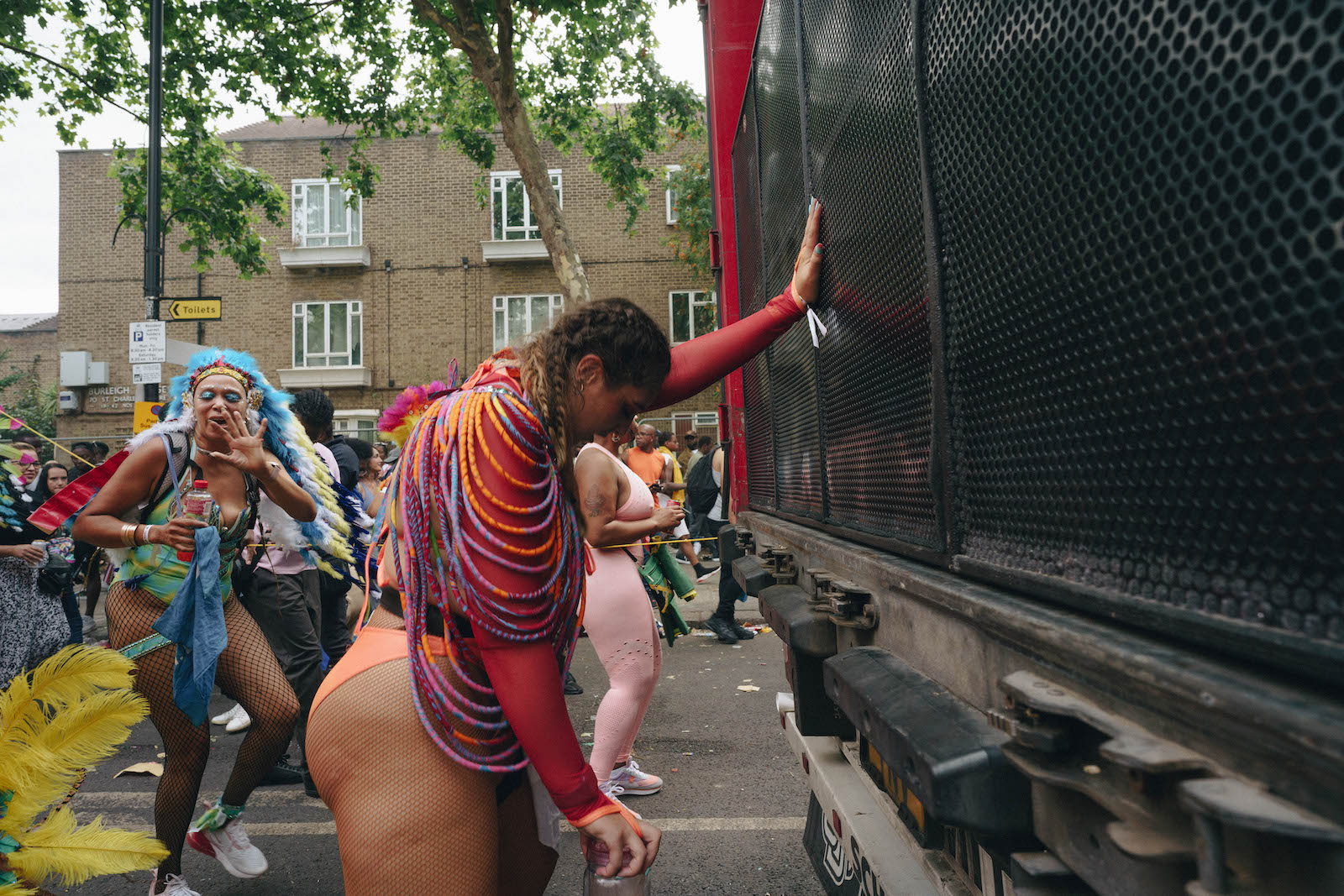A girl leaning against a vehicle with a drink at Notting Hill Carnival 2022