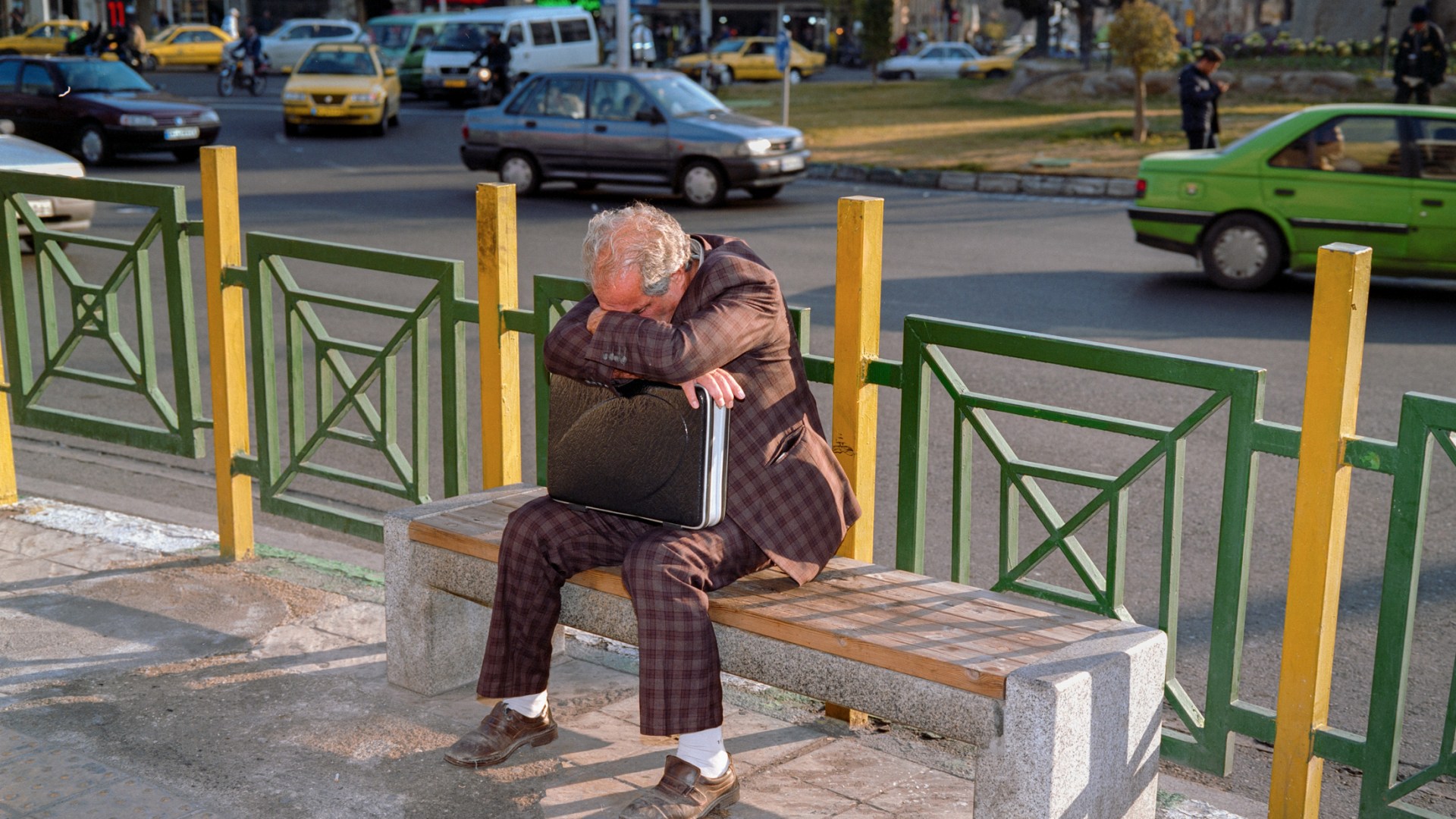 A man sits with his head on his brief case